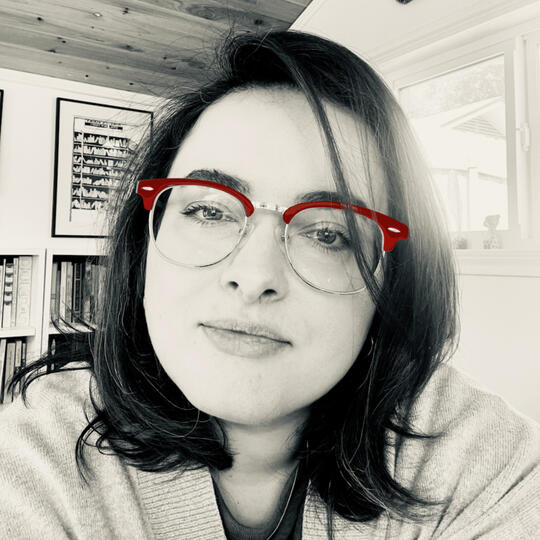 Portrait of Allegra Villarreal — black-and-white with red glasses, books in the background